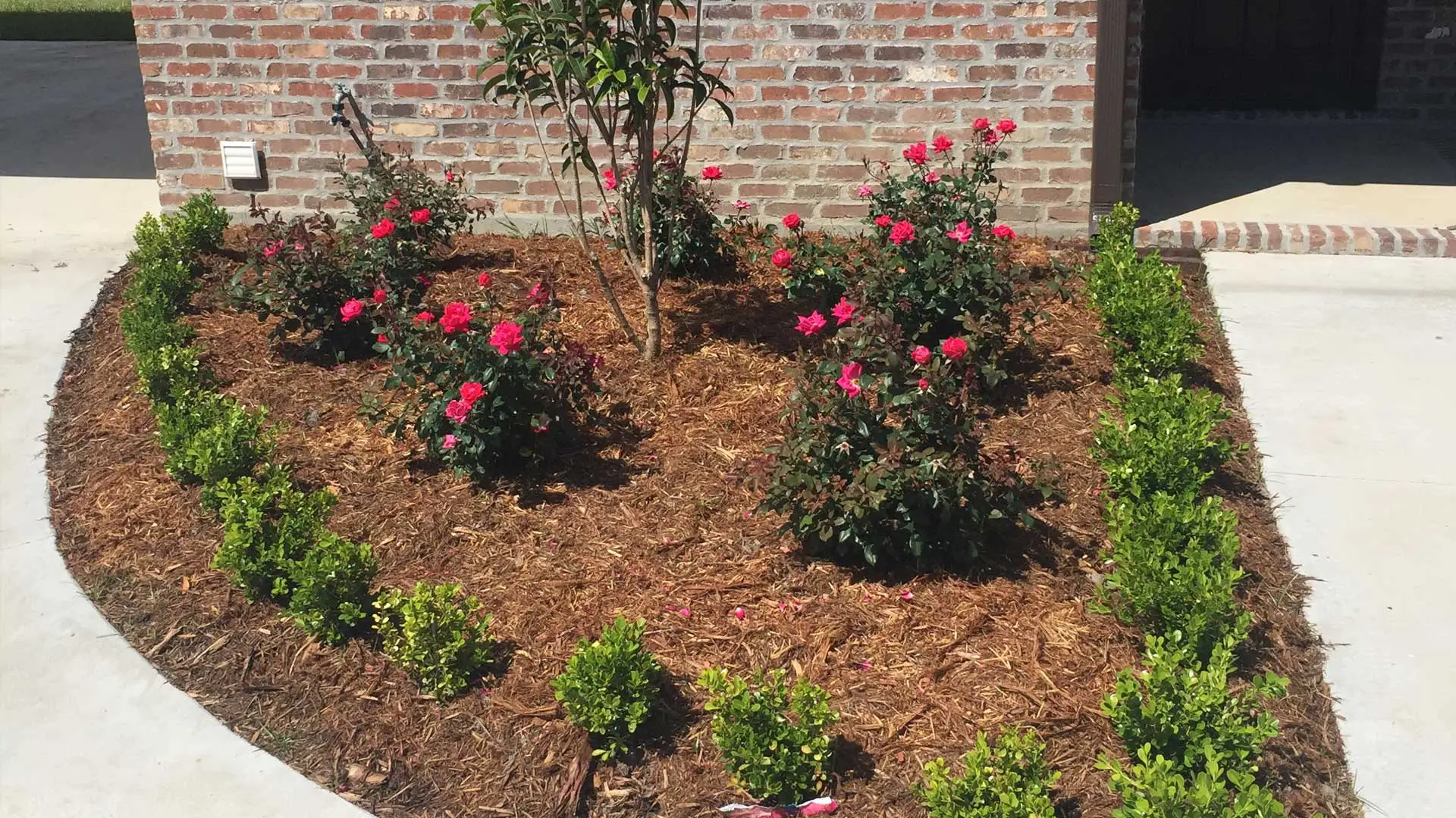 New landscaping with flowers, shrubs, and mulch in front of an Houma home.